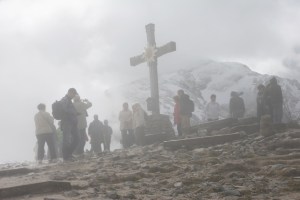 Fog and clouds cover the cross on the mountaintop
